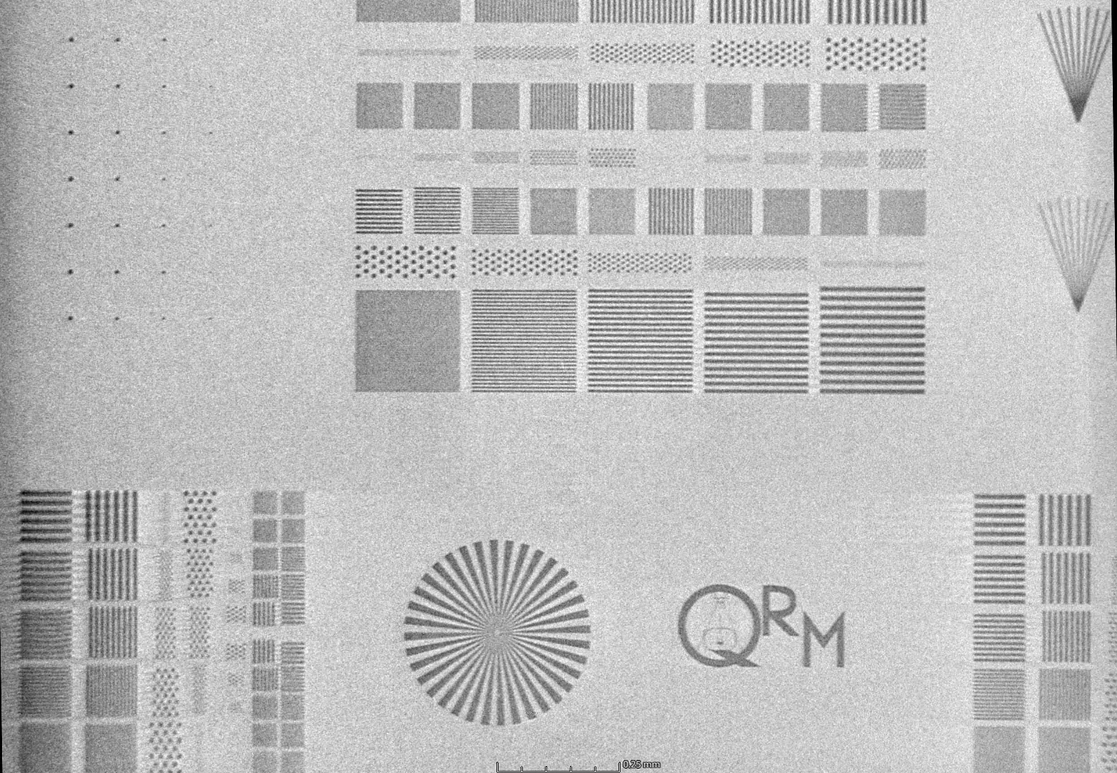 Das dargestellte µCT-Bild zeigt ein QRM-Auflösungsphantom bei einer Voxelgröße von 1 µm. Sichtbar sind strukturierte Testfelder mit Linienpaaren unterschiedlicher räumlicher Frequenz, Punktmustern sowie radialen Strukturen zur isotropen Bewertung der Auflösung. Die feinen Linienmuster ermöglichen die Bestimmung der Grenzauflösung durch Identifikation der kleinsten noch trennbaren Strukturen. Ergänzend erlauben homogene Flächen und periodische Muster die Analyse von Bildrauschen, Kontrast und Artefakten, wodurch eine umfassende Charakterisierung der Bildqualität des µCT-Systems erfolgt.